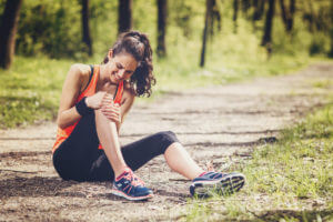 Athletic woman sitting on the ground with knee pain