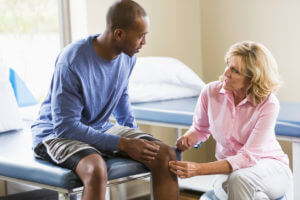 Doctor examining a male patient's knee