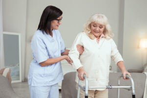 A Nurse helping older lady in walking after Hip surgery