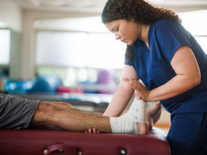 therapist holding ankle sprained of patient