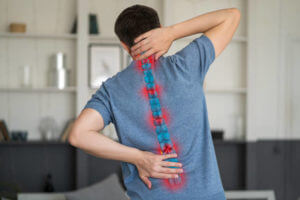 Intervertebral hernia, neck and lumbar pain, man suffering from backache at home, spinal disc disease, painful area highlighted in red