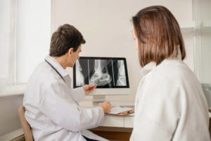 Young man doctor explain to the woman patient the result of x ray that show fracture of her calcaneus