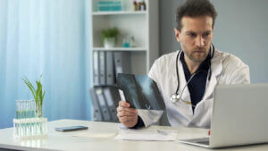 orthopedic Surgeon studying x-ray of bone and making prescription