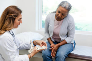 Female orthopedic surgeon explains foot injury to senior woman