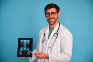 Image of a male spine specialist holding a tablet with a backbone x-ray.