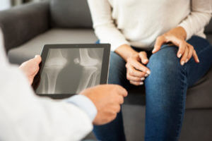Woman getting her knee X-ray image examined to determine if she is a candidate for total knee arthroplasty.