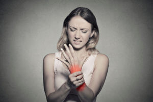 A woman is holding her wrist in pain as she experiences discomfort in that area.